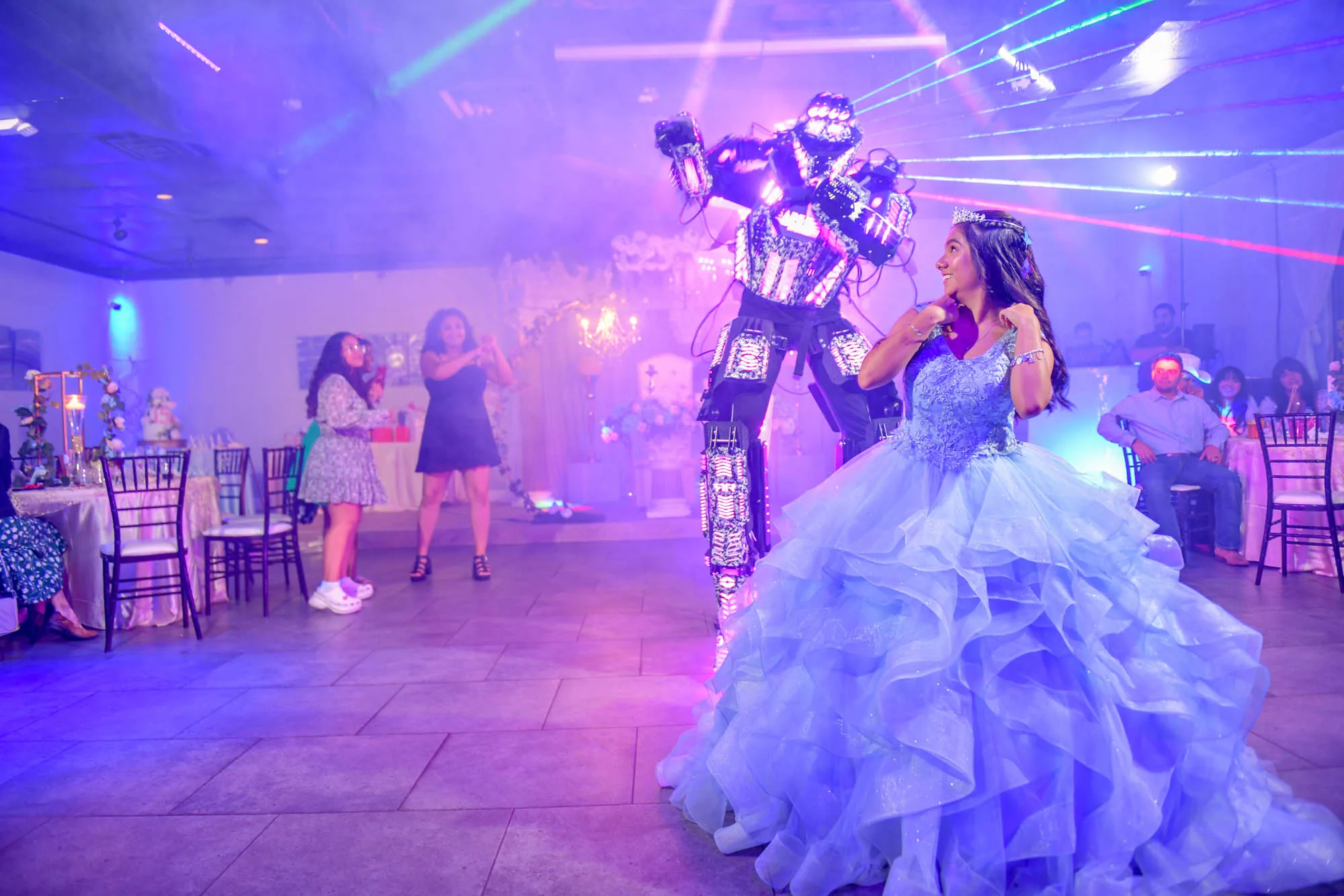 A quinceanera celebrant dancing with an LED robot performer under lasers on the Moonlight Ballroom dance floor