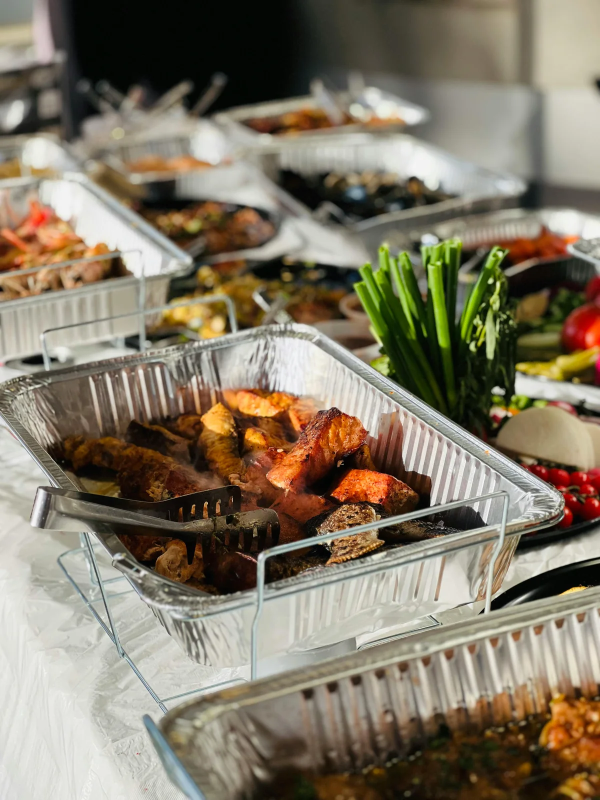 A catered buffet spread of trays and fresh vegetables