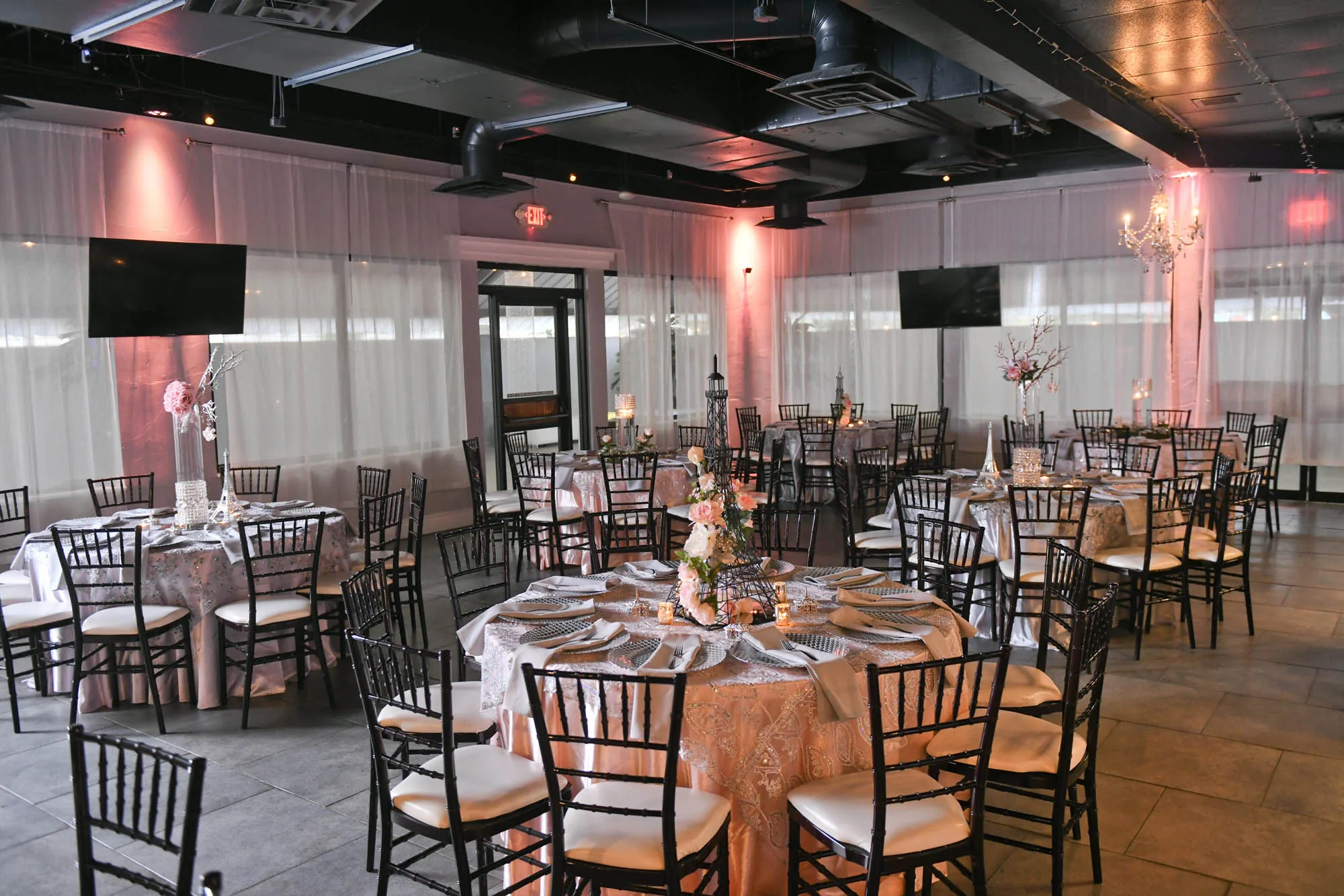 The Moonlight Ballroom set for a reception with round tables, chiavari chairs, floor-length linens, and pink uplighting